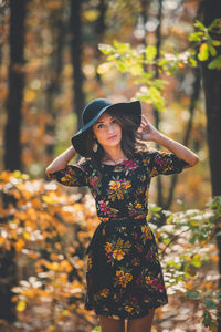 Young woman wearing hat while standing on tree