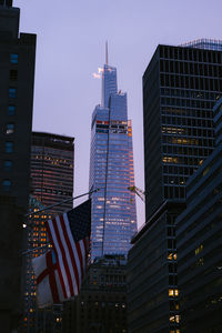 High rise bank of america tower with glass walls located on street of midtown manhattan neighborhood of new york city in evening