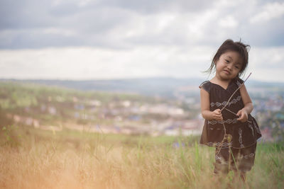 Girl standing on field against sky