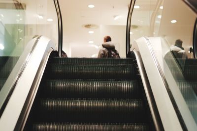 Rear view of woman on escalator