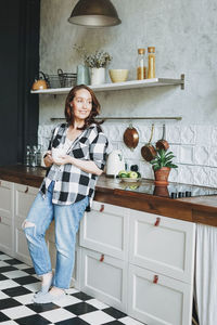 Smiling woman looking away while standing in kitchen