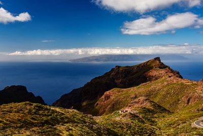 Scenic view of rocky mountains by sea against sky