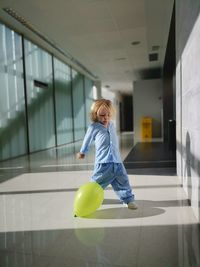 Full length of cute boy with balloons in building