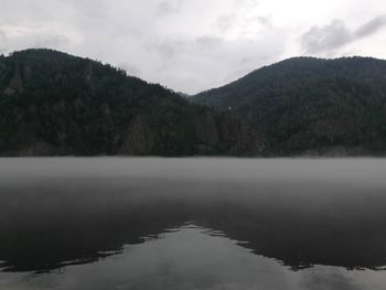 Scenic view of lake by mountains against sky