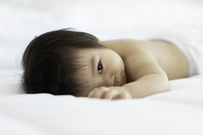 Close-up portrait of cute baby lying on bed