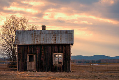 Abandoned barn on field against sky during sunset