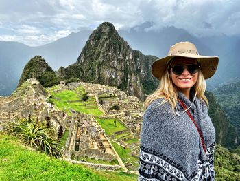 Portrait of smiling woman wearing hat while standing against mountain