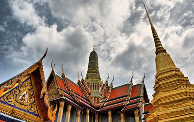 Low angle view of wat phra kaew temple against cloudy sky