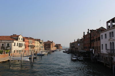 Canal amidst buildings in city against clear sky