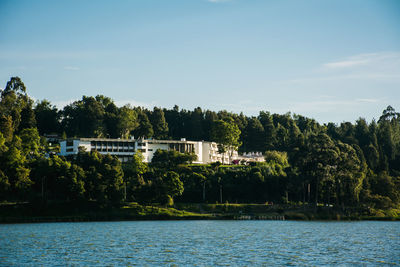 River by trees and buildings against sky