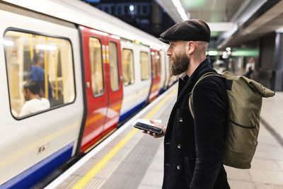 Commuter holding smart phone and waiting for train at station