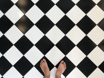 Low section of person standing on tiled floor