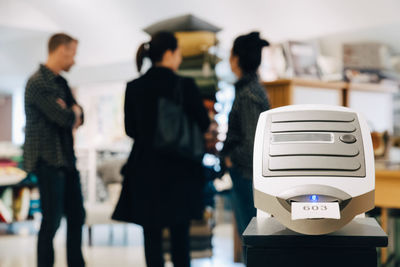 Machine in store while people discussing in background