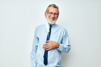 Portrait of senior man standing against white background