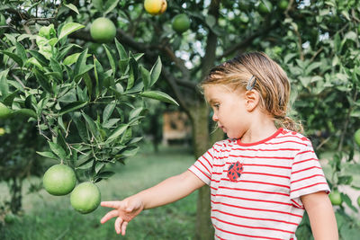 Girl standing by fruit tree in yard