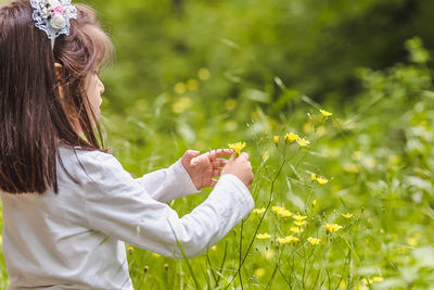 Side view of woman holding flower on field