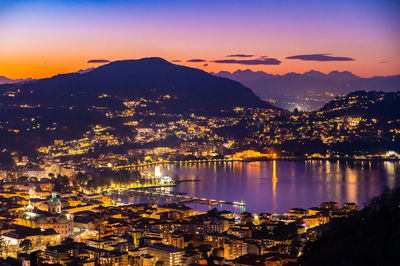 The city of como, in the evening, with the lakefront, the cathedral, and the surrounding mountains.