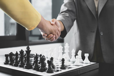 Men shaking hands over chess board