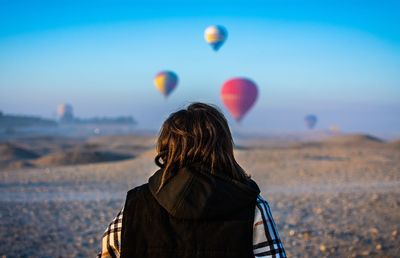 Rear view of woman on land against sky during winter