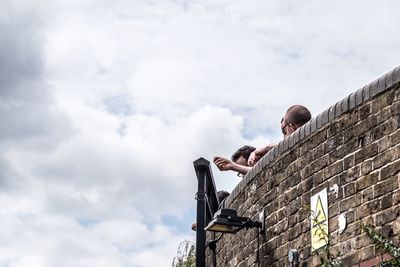 Low angle view of man on retaining wall against sky