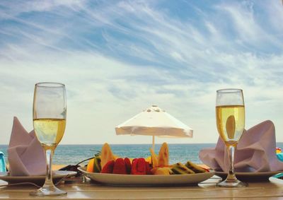 View of wine glasses on beach against sky