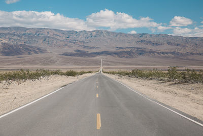 Road by mountains against sky