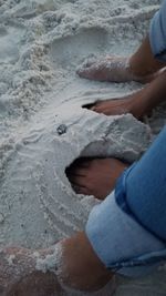 Low section of person holding sand on beach