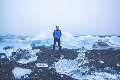 Portrait of man standing by ice formations at beach