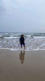 Rear view of man on beach against sky