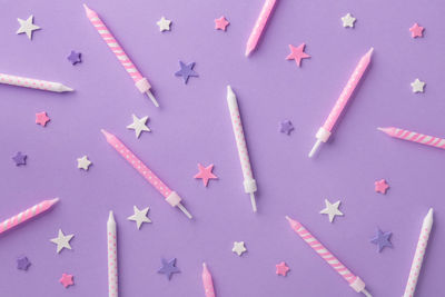 Close-up of multi colored candles and star shape decoration over purple background