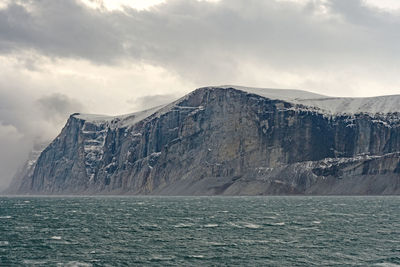 High cliffs under dramatic clouds in the sam ford fjord on baffin island in nunavut, canada