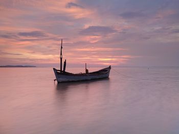 Fishing boat in sea against sky during sunset