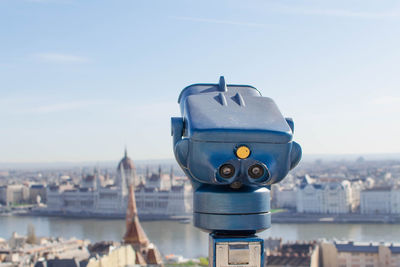 Close-up of coin-operated binoculars against buildings in city