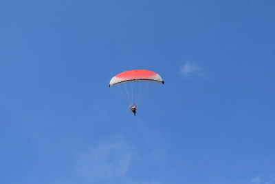 Low angle view of person parachuting against blue sky