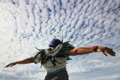 Low angle view of woman standing against cloudy sky