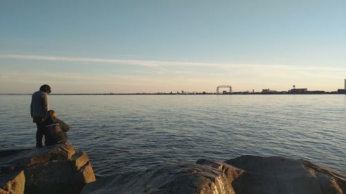 Women at rock in lake superior against sky