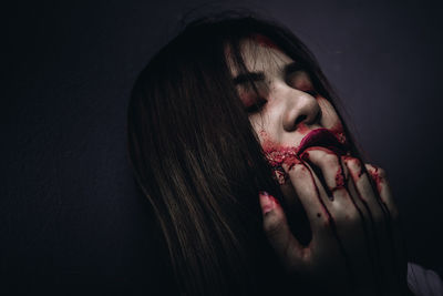 Portrait of young woman with halloween make-up against wall