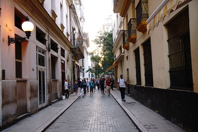 People walking on footpath amidst buildings in city