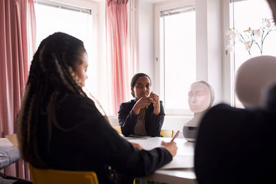 Businesswomen discussing robot voice assistant during meeting