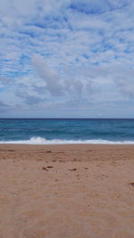 Scenic view of beach against cloudy sky