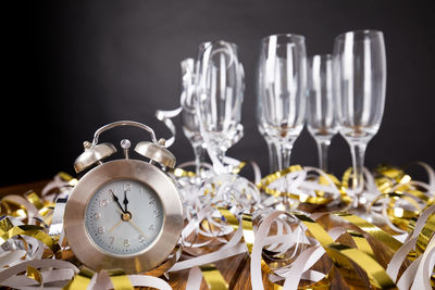 Close-up of alarm clock and wineglasses on streamers against black background