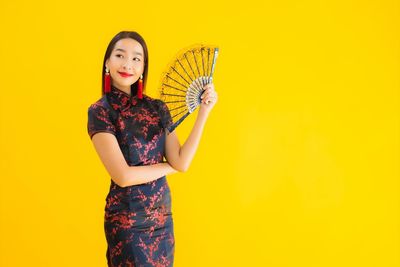 Portrait of a beautiful young woman against yellow background