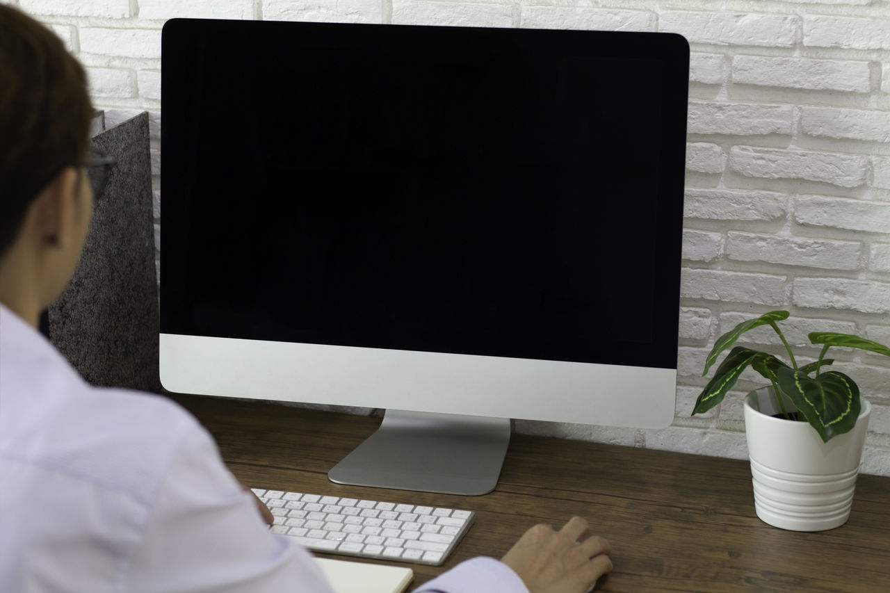 REAR VIEW OF WOMAN USING LAPTOP