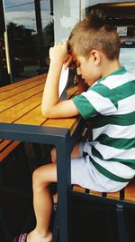 Side view of boy sitting seen through glass