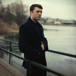 Man standing on bridge over lake