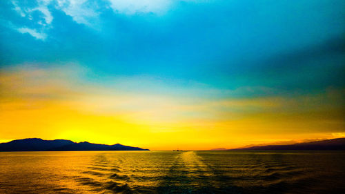 Scenic view of sea against dramatic sky during sunset