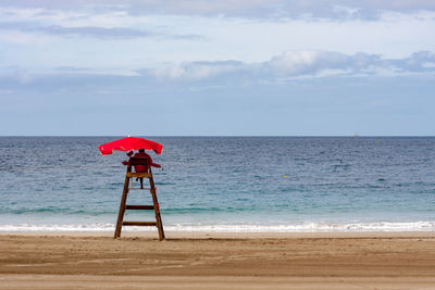 Lifeguard chair on beach against sky