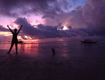 Silhouette people on beach against sky during sunset