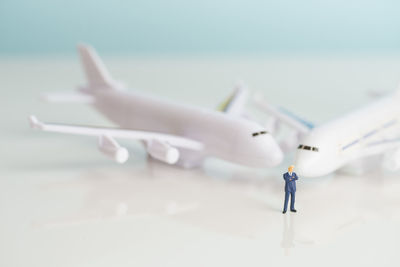 High angle view of airplane models and pilot figurine on table against blue background