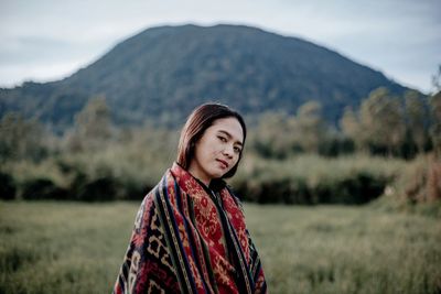Portrait of woman standing on field against mountains